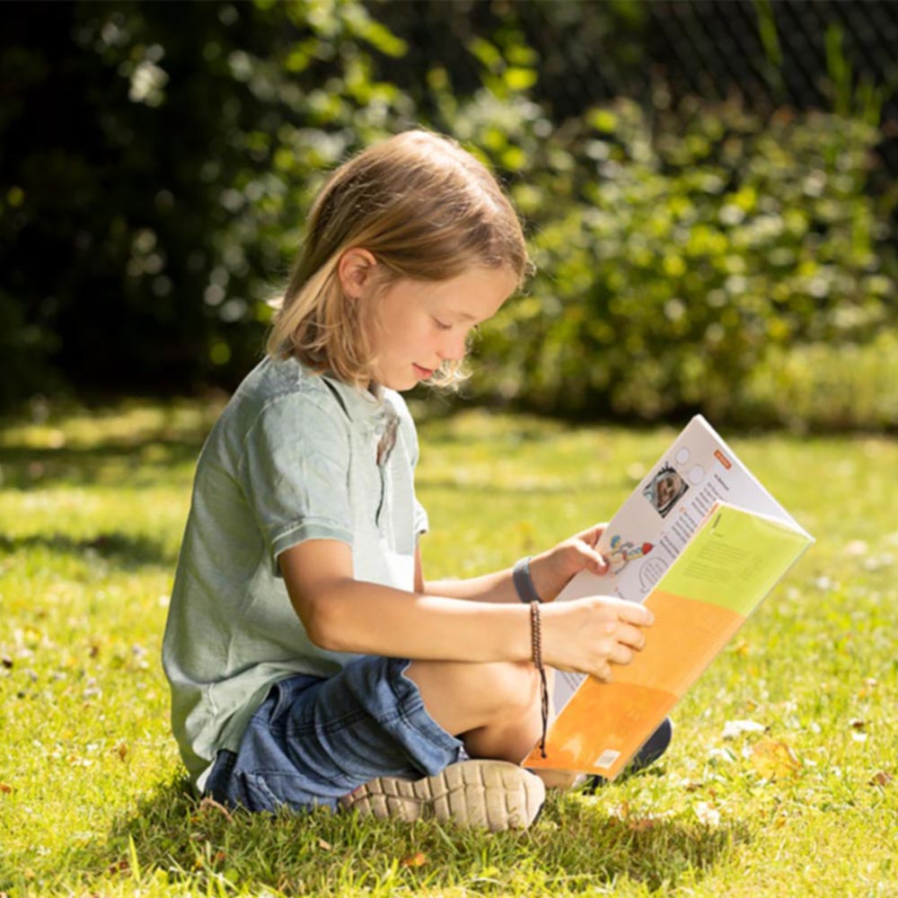 Kind lernt im Garten für die Schule.