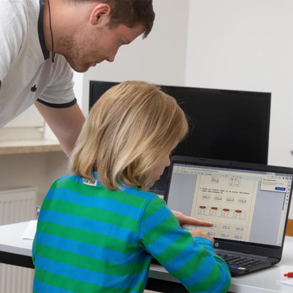 Nachhilfelehrer gibt einem Schüler Nachhilfe, dabei wird direkt am Computer gearbeitet.